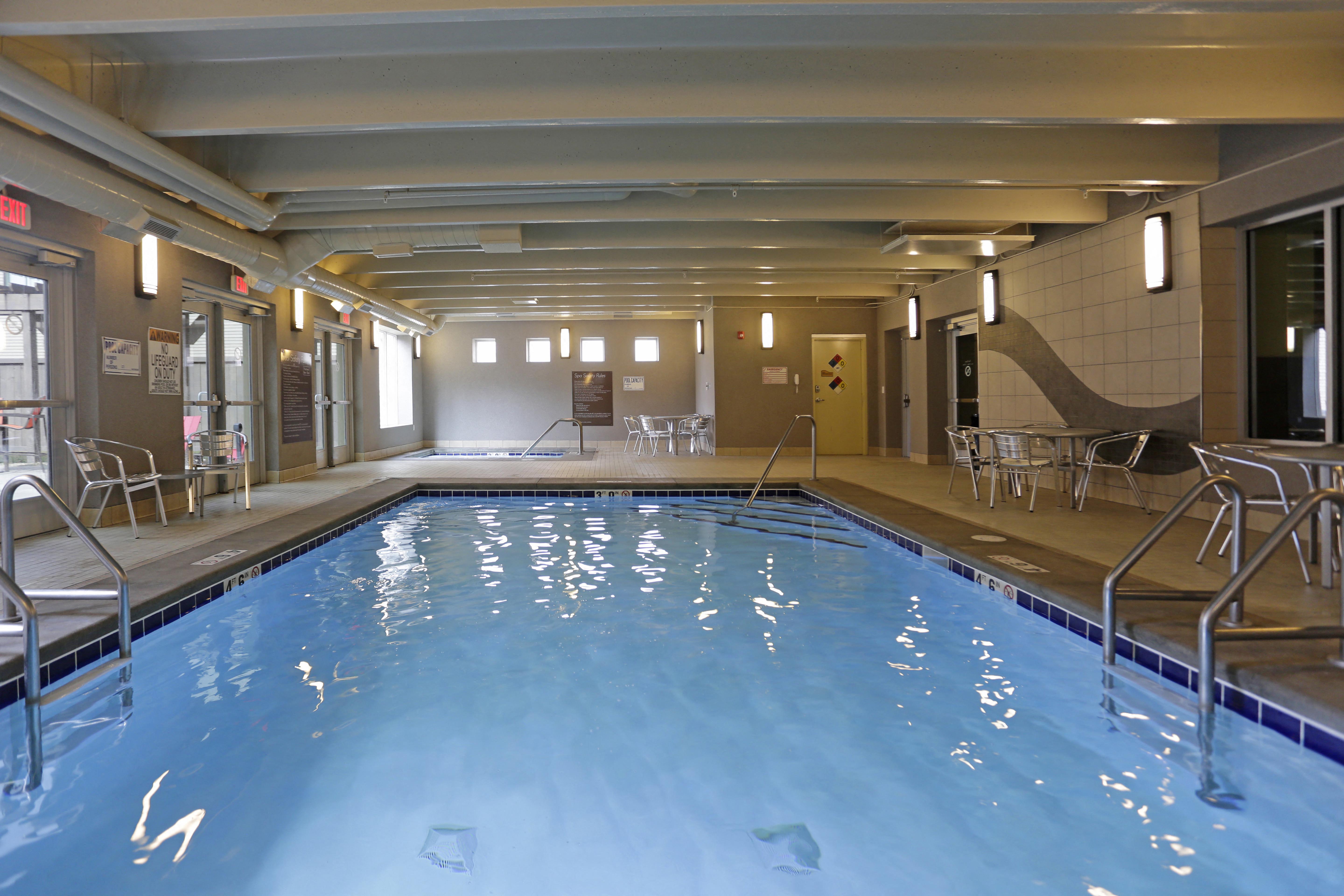 View of the indoor pool stretching from one end to the other. Indoor hot tub can be seen on the opposite end of the room.